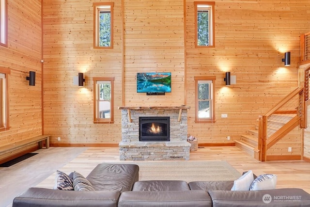 living area featuring baseboards, a towering ceiling, wood finished floors, and wooden walls