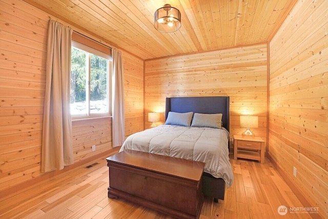 bedroom featuring wood walls, visible vents, wood ceiling, and light wood-style flooring