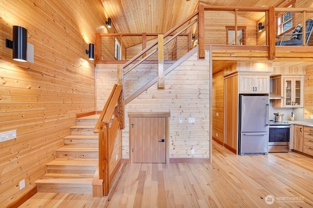 staircase with wood ceiling, wood walls, high vaulted ceiling, baseboards, and hardwood / wood-style floors