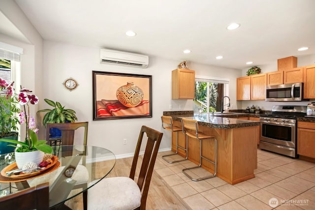kitchen featuring appliances with stainless steel finishes, a wall unit AC, a sink, recessed lighting, and a peninsula