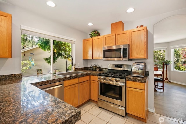 kitchen with appliances with stainless steel finishes, a sink, tile countertops, and recessed lighting