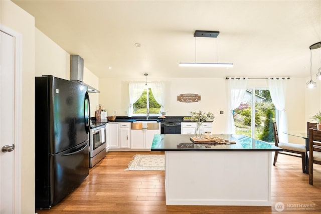 18514 71st St NW, Vaughn, WA 98394 - kitchen with black appliances, wall chimney range hood, dark countertops, and plenty of natural light