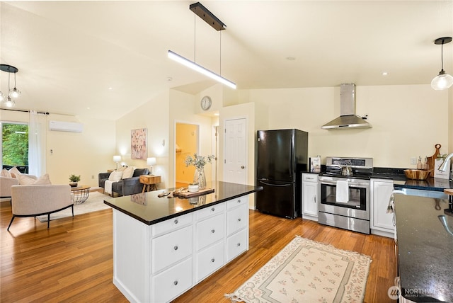 18514 71st St NW, Vaughn, WA 98394 - kitchen featuring stainless steel range with electric cooktop, wall chimney range hood, freestanding refrigerator, dark countertops, and an AC wall unit