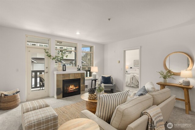 living area featuring visible vents, a tile fireplace, and light colored carpet