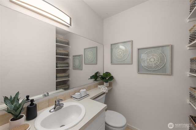 half bath featuring vanity, baseboards, and toilet