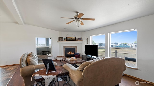 living area featuring a ceiling fan, baseboards, vaulted ceiling with beams, and a tile fireplace