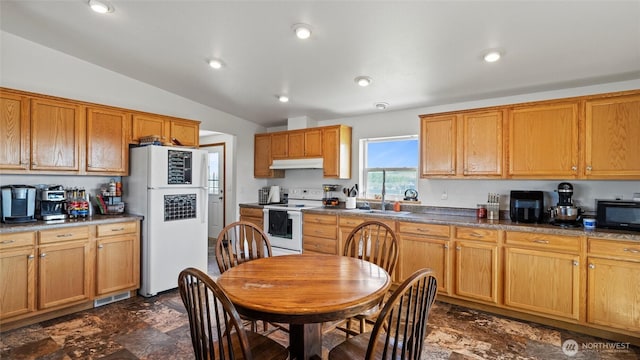 kitchen featuring a sink, white appliances, stone finish flooring, under cabinet range hood, and vaulted ceiling