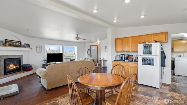 dining space with washer / dryer, a ceiling fan, a fireplace, and vaulted ceiling