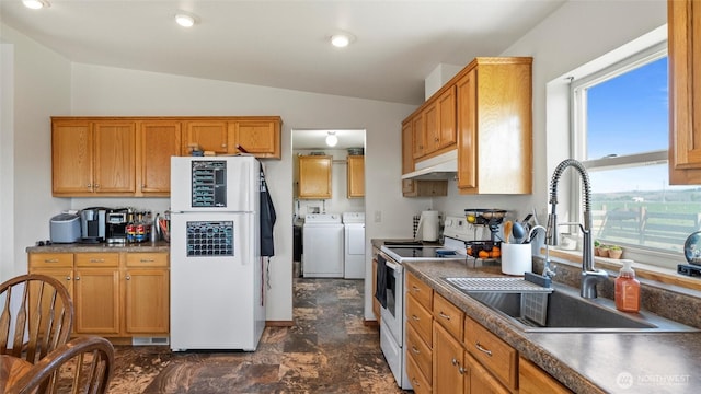 kitchen featuring a sink, lofted ceiling, under cabinet range hood, white appliances, and washer and clothes dryer