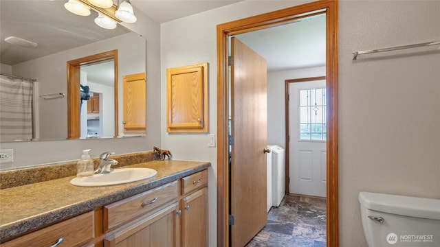 bathroom featuring toilet, stone finish flooring, and vanity