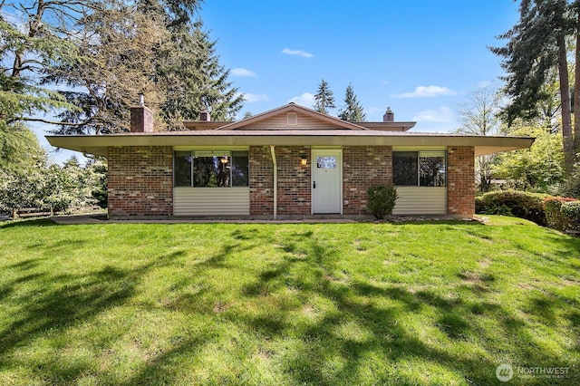 single story home with a chimney, brick siding, and a front yard