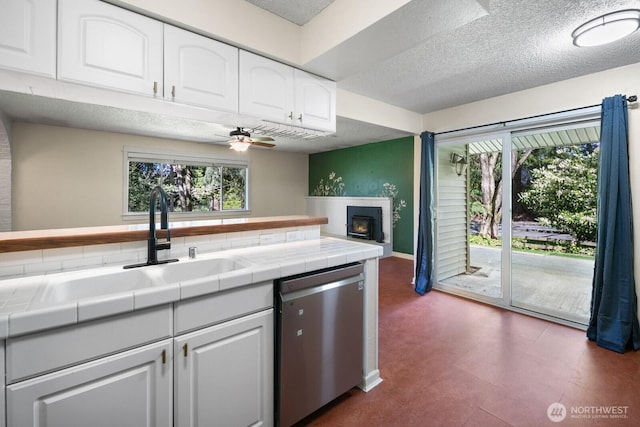 kitchen featuring tile counters, a textured ceiling, white cabinetry, a ceiling fan, and dishwasher