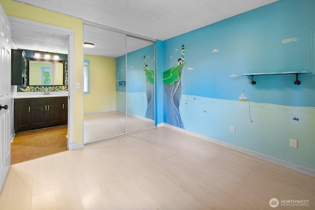 bathroom with vanity, baseboards, a textured ceiling, and wood finished floors