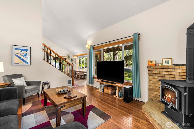 living area with a wood stove, stairway, wood-type flooring, lofted ceiling, and baseboards