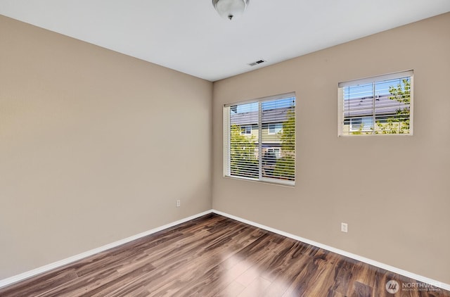 spare room with baseboards, wood finished floors, and visible vents