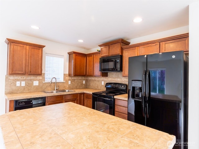 kitchen featuring tasteful backsplash, brown cabinets, a sink, black appliances, and recessed lighting
