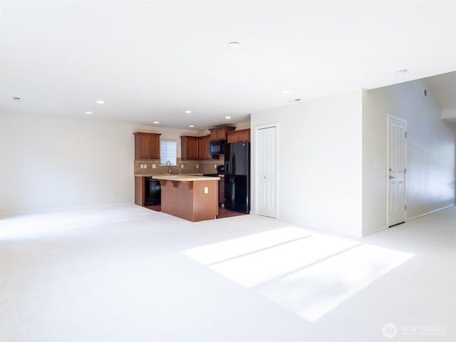 unfurnished living room with a sink, recessed lighting, and light colored carpet