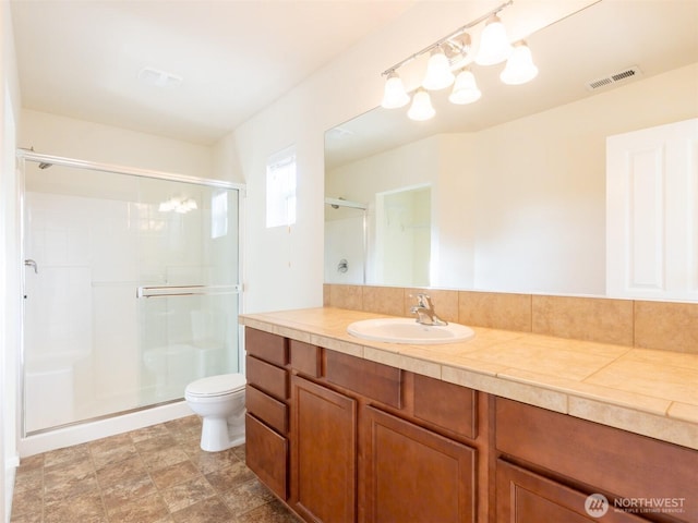 bathroom with vanity, a stall shower, toilet, and visible vents