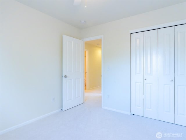 unfurnished bedroom with baseboards, light carpet, and a closet