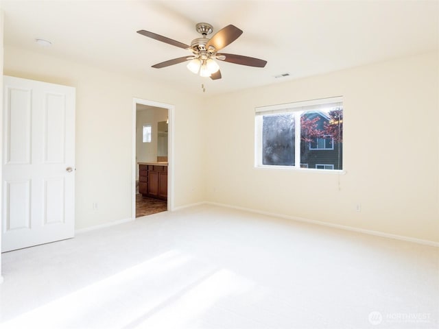 unfurnished bedroom featuring a ceiling fan, visible vents, carpet floors, baseboards, and connected bathroom
