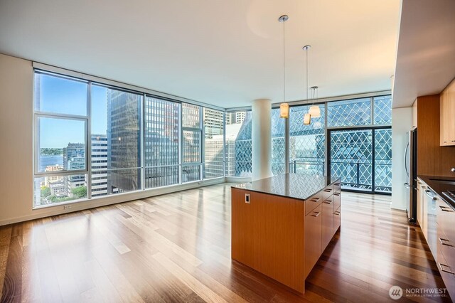 909 5th Ave Unit 701, Seattle, WA 98104 - kitchen with dark countertops, light wood-style flooring, floor to ceiling windows, and a kitchen island