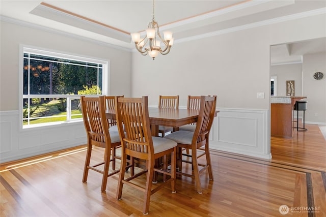 dining area with crown molding, light wood-style floors, and a notable chandelier