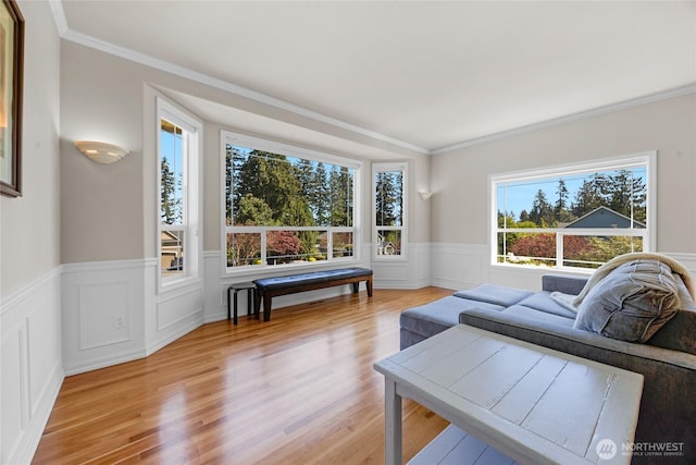 living area with light wood-style floors, plenty of natural light, and wainscoting
