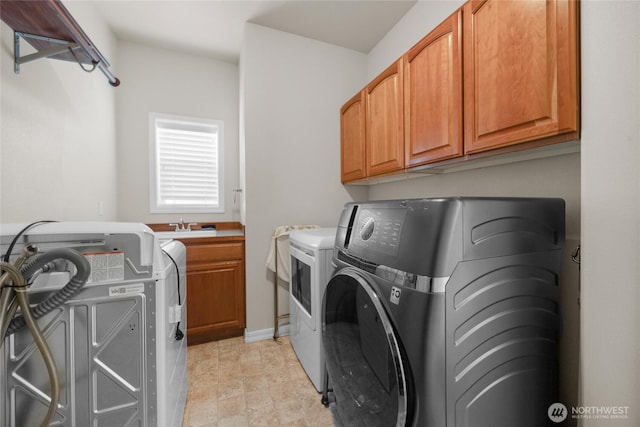 washroom with cabinet space, a sink, stone finish floor, baseboards, and washer and clothes dryer