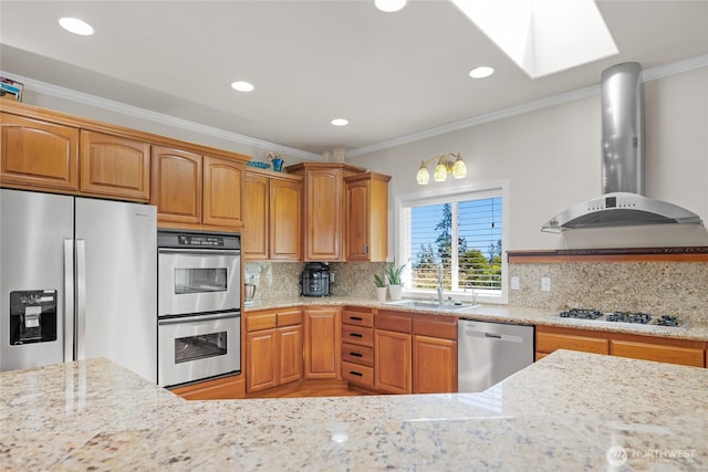 kitchen with appliances with stainless steel finishes, a sink, wall chimney exhaust hood, a skylight, and ornamental molding