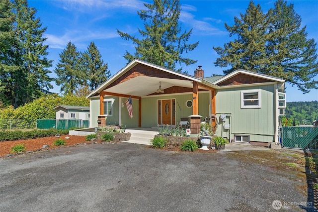 7295 Navajo Trl NE, Bremerton, WA 98311 - view of front of house with a porch, a chimney, a ceiling fan, and a carport