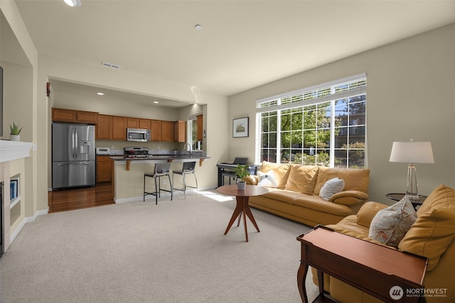 living room with dark colored carpet, recessed lighting, baseboards, and a glass covered fireplace