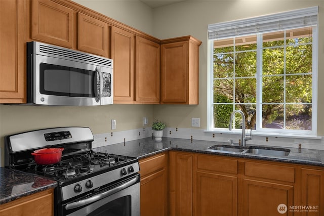 kitchen with stainless steel appliances, a sink, plenty of natural light, and brown cabinetry