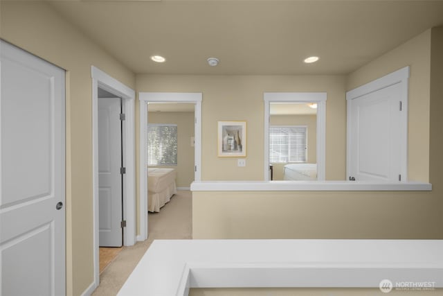 corridor featuring recessed lighting, light carpet, and baseboards