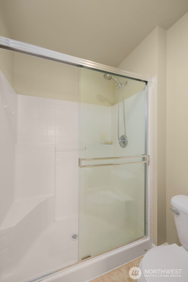 bathroom featuring toilet and a shower stall