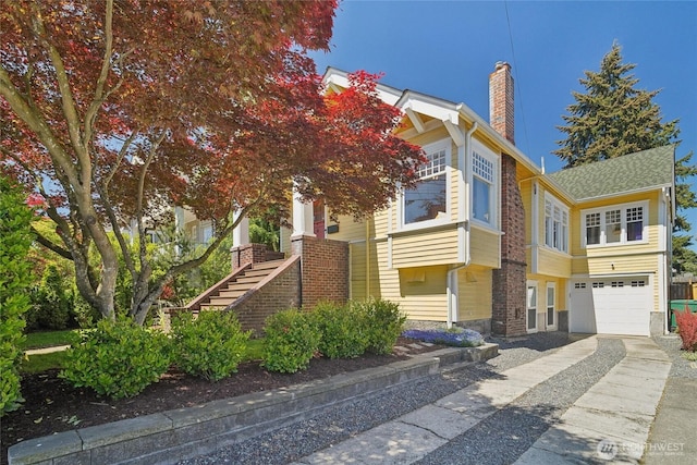 view of front of house featuring concrete driveway, stairs, a garage, and a chimney