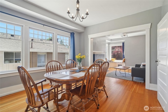 dining space with a chandelier, light wood finished floors, and baseboards