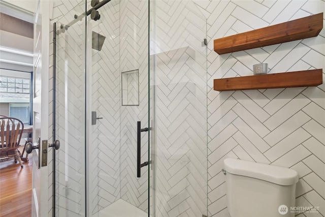 full bath featuring a stall shower, toilet, and wood finished floors