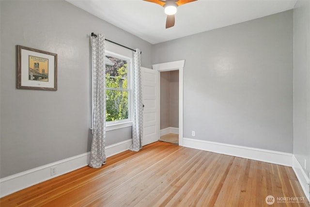 spare room featuring a ceiling fan, baseboards, and light wood finished floors