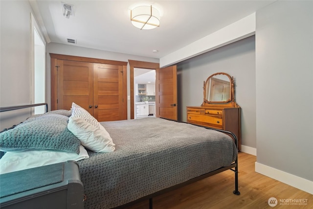bedroom with a closet, wood finished floors, and baseboards
