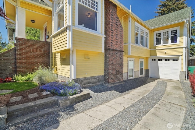 view of home's exterior featuring driveway, a garage, brick siding, and a shingled roof