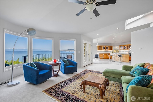 living area with ceiling fan, lofted ceiling, a water view, light carpet, and recessed lighting