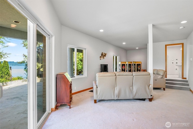living room with baseboards, a water view, recessed lighting, and light colored carpet
