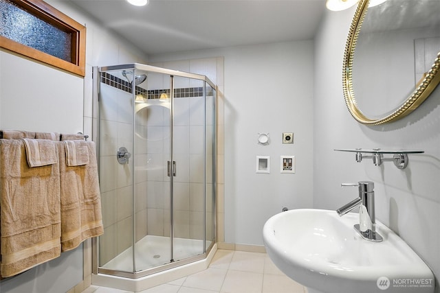 bathroom with baseboards, a sink, tile patterned flooring, and a stall shower