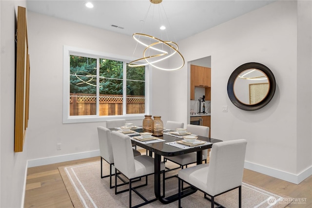 dining room with light wood-type flooring, baseboards, and visible vents