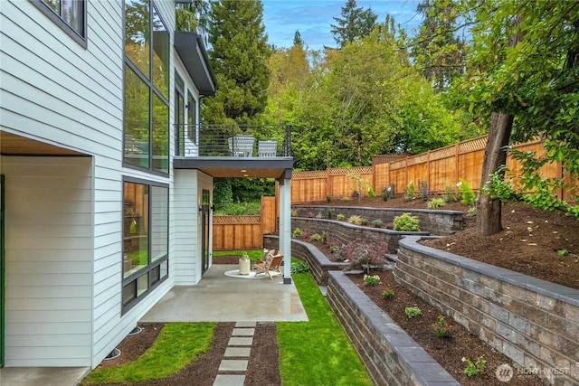 view of yard with a fenced backyard, a patio area, and a balcony