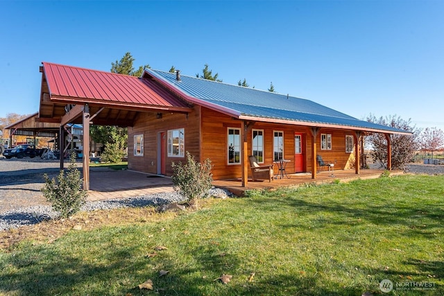 back of property featuring a lawn and metal roof