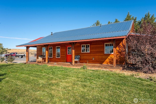 rear view of property featuring a lawn and metal roof