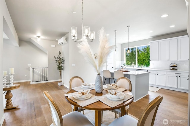 dining space featuring a notable chandelier, light wood-style flooring, recessed lighting, baseboards, and a wall mounted AC
