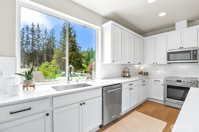 kitchen featuring decorative backsplash, a sink, light countertops, stainless steel appliances, and light wood-style flooring