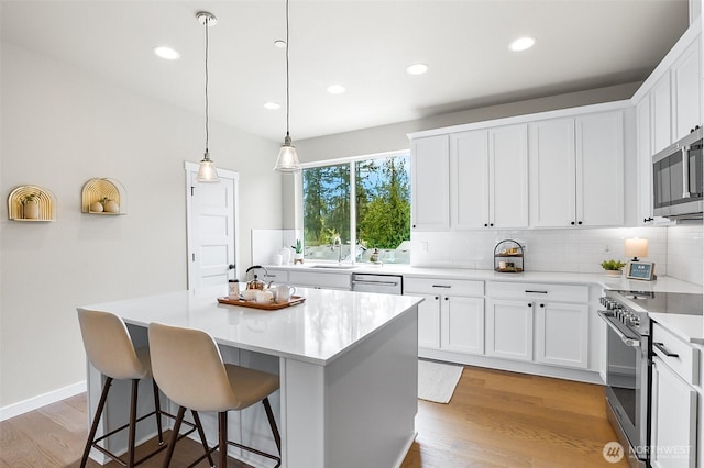 kitchen with a kitchen island, backsplash, stainless steel appliances, and white cabinetry